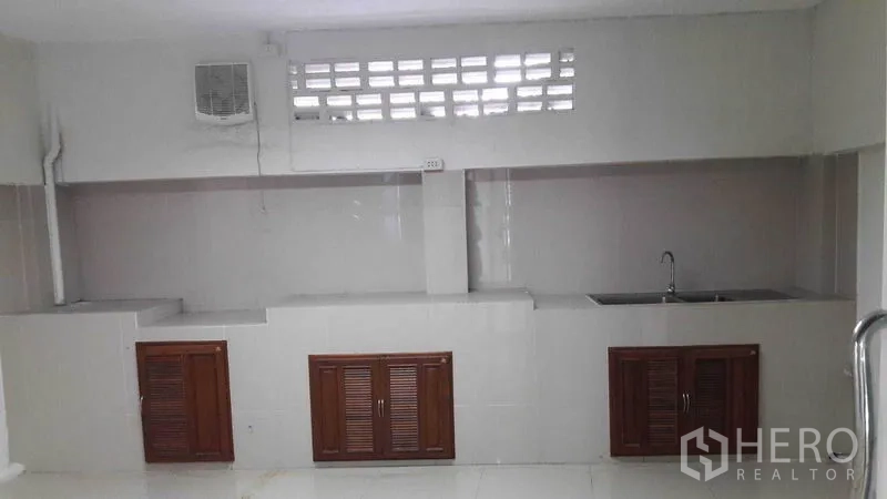 Office Space for rent in Bueng Kum, Bangkok - Long pantry with countertop, sink, ventilation blocks and wooden cabinet doors.