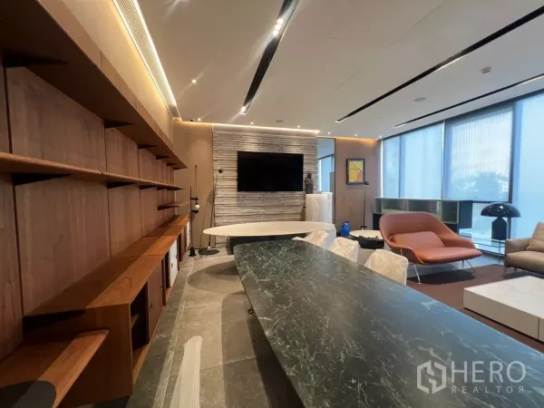 พื้นที่ขายปลีก ให้เช่า - ผนังตู้บิลต์อินลายไม้ ผนังหินพร้อมทีวีแขวน และโต๊ะหินอ่อนสีเขียวในโซนโชว์รูม.