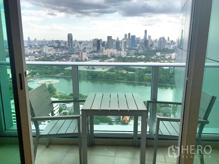 คอนโด ให้เช่าในKhlong Toei, Bangkok - ระเบียงชั้นสูงพร้อมโต๊ะเก้าอี้ มองเห็นวิวทะเลสาบสวนเบญจกิติและสกายไลน์กรุงเทพฯ