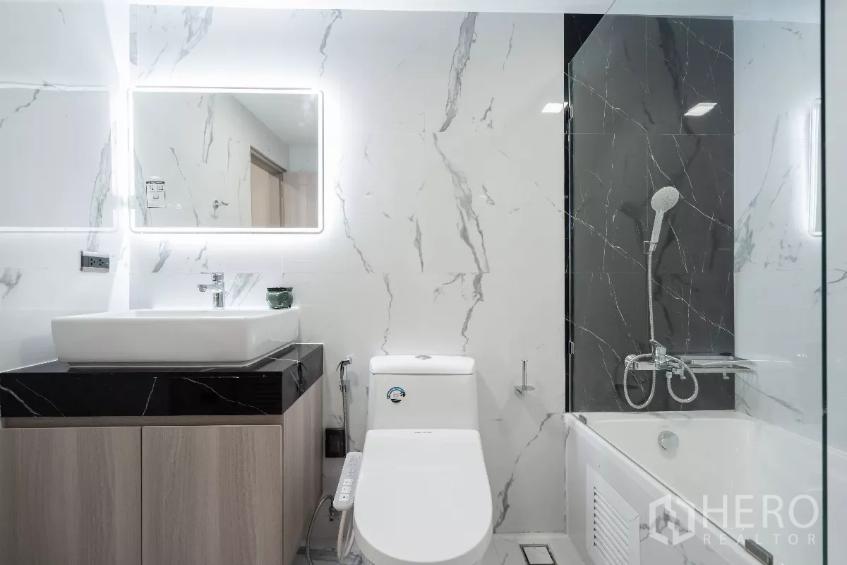 Apartment for rent - Bathroom close-up showing vanity, toilet and bathtub with handheld shower against a black accent wall.