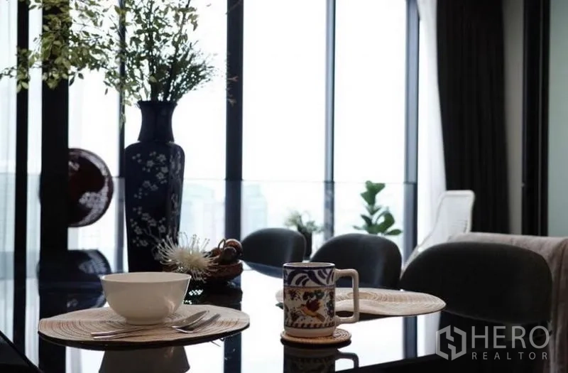 คอนโด ให้เช่า - ภาพระยะใกล้โต๊ะอาหารพร้อมแจกันและชุดจานชามริมหน้าต่าง