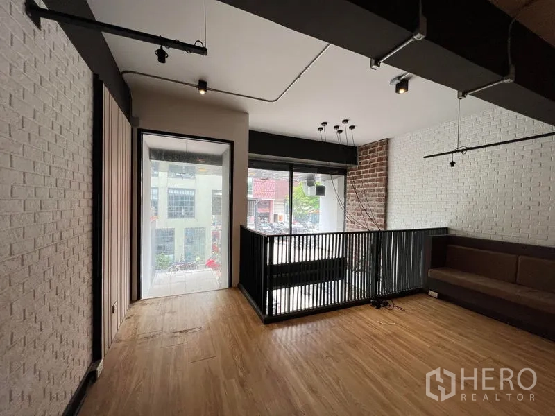 店屋 出租 - 夹层休息区，金属栏杆、红砖点缀墙与临街窗景。