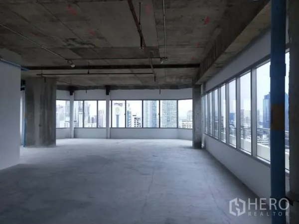 Office Space for rent in Watthana, Bangkok - Corner bare-shell office with wraparound windows, exposed ceiling and skyline view.