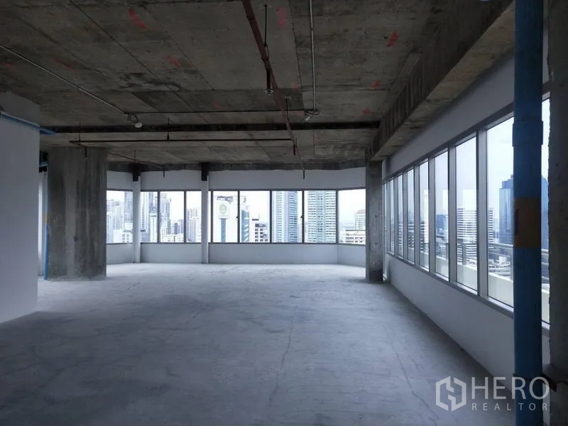 Office Space for rent in Watthana, Bangkok - Corner bare-shell office with wraparound windows, exposed ceiling and skyline view.
