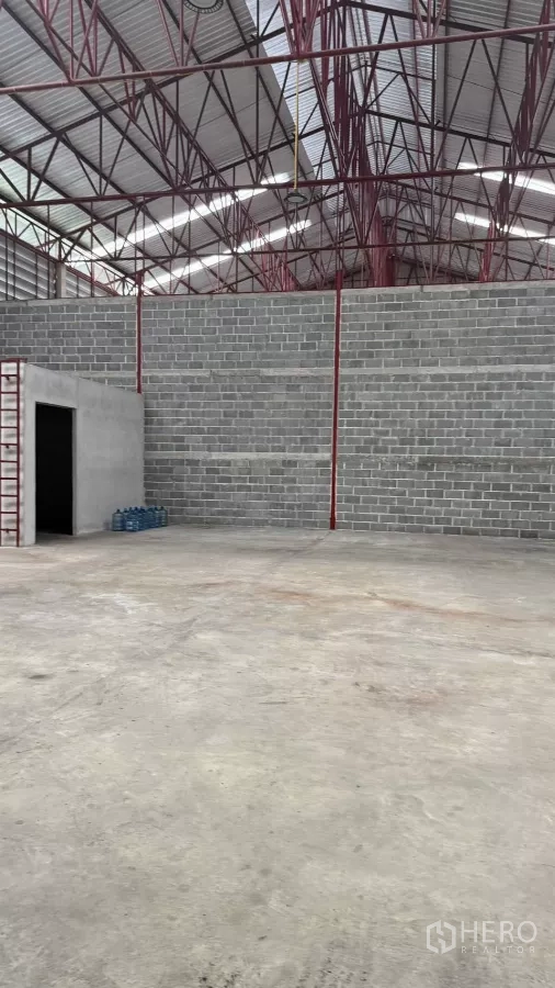 Warehouse for rent in Min Buri, Bangkok - Close-up of block wall partition with doorway inside spacious industrial warehouse.