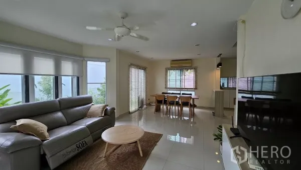 独立式住宅 出租在Khlong Toei, Bangkok - 明亮的客餐厅一体空间，皮质沙发、电视墙、大窗与亮面地砖。