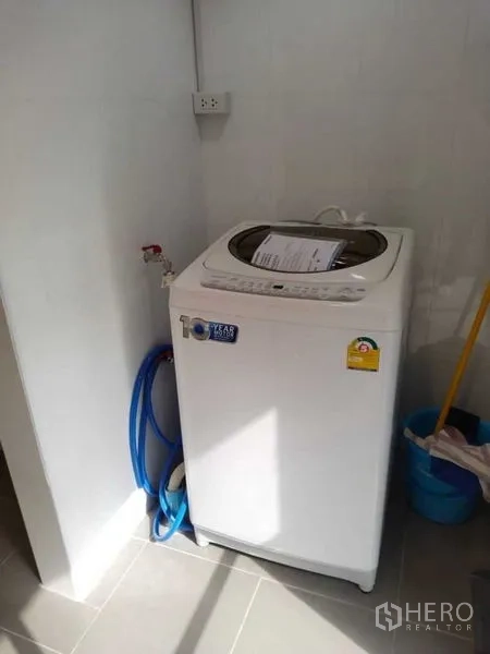 Condominium for rent in Sathon, Bangkok - Top-load washing machine in a utility corner with water connections.