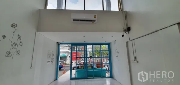 Home Office for rent in Khlong Toei, Bangkok - Double-height entry with blue glass doors, white walls and simple wall illustrations.