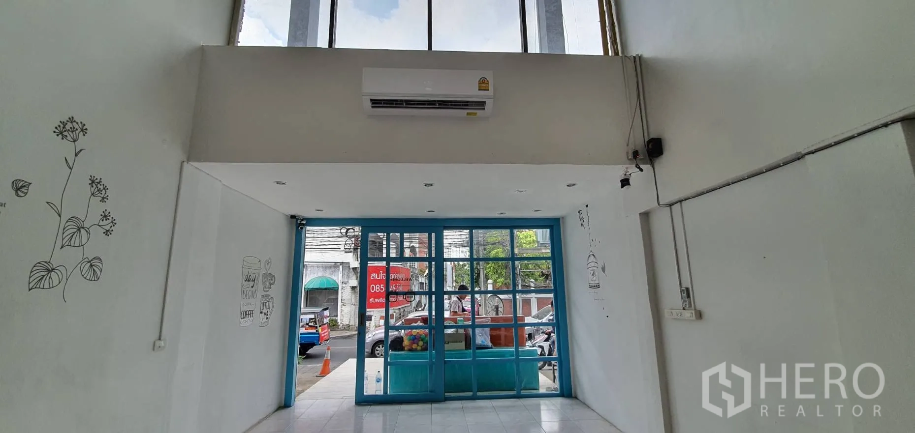 Home Office for rent in Khlong Toei, Bangkok - Double-height entry with blue glass doors, white walls and simple wall illustrations.