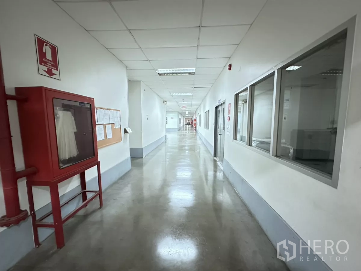 โรงงาน ขายในLat Krabang, Bangkok - ทางเดินยาวมีตู้สายฉีดน้ำดับเพลิง และช่องหน้าต่างมองเข้าไปยังพื้นที่ผลิต
