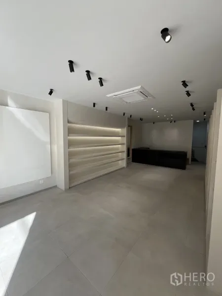 零售空间 出租在Bangkok - 极简零售内饰，瓷砖地面、筒灯与发光展示层架