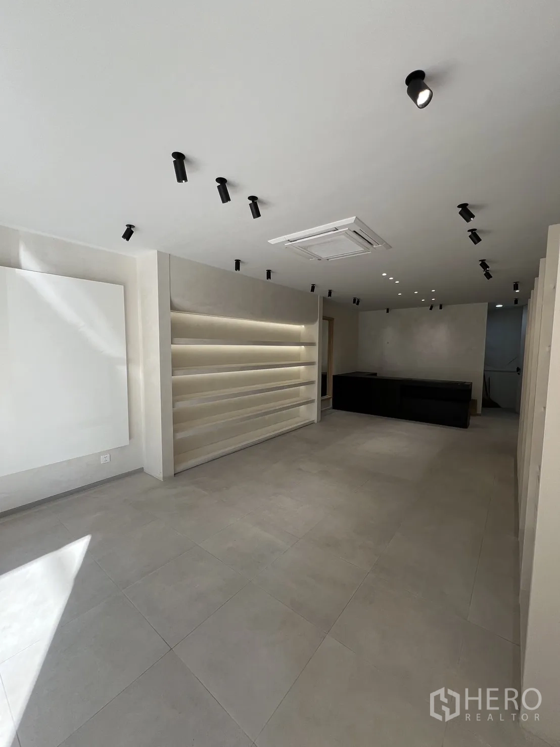 零售空间 出租在Bangkok - 极简零售内饰，瓷砖地面、筒灯与发光展示层架