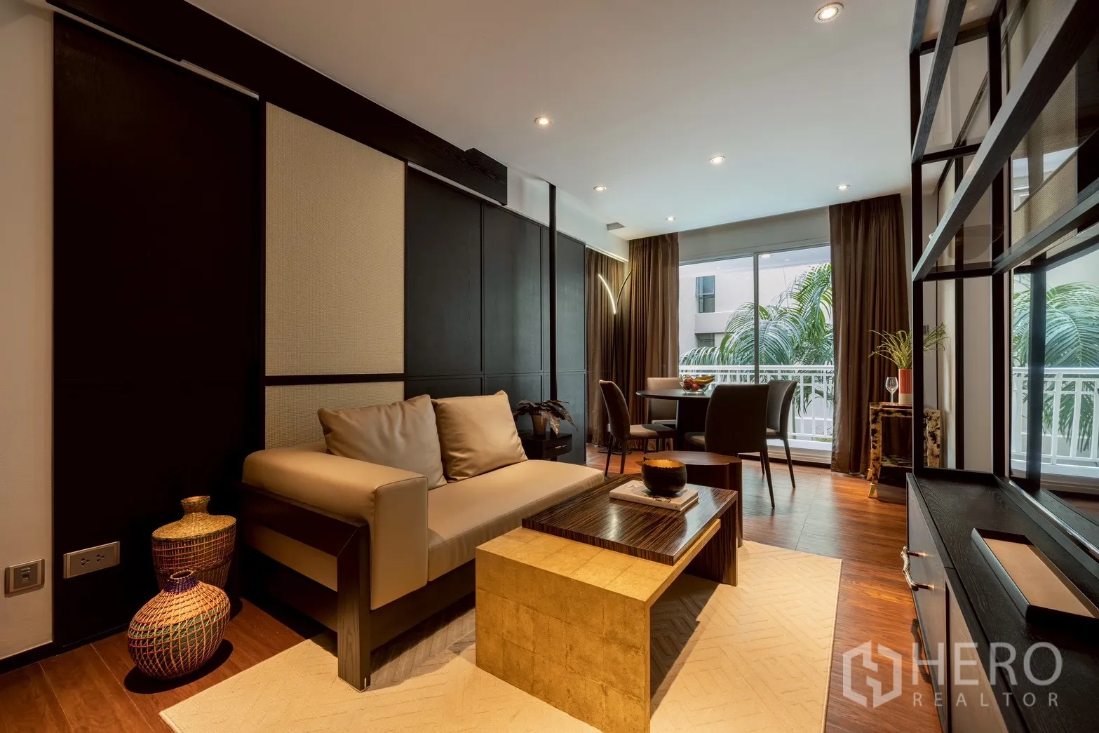 公寓 for rent or sale in Pathum Wan, Bangkok - 开放式客厅，米色沙发、木地板与阳台绿景。