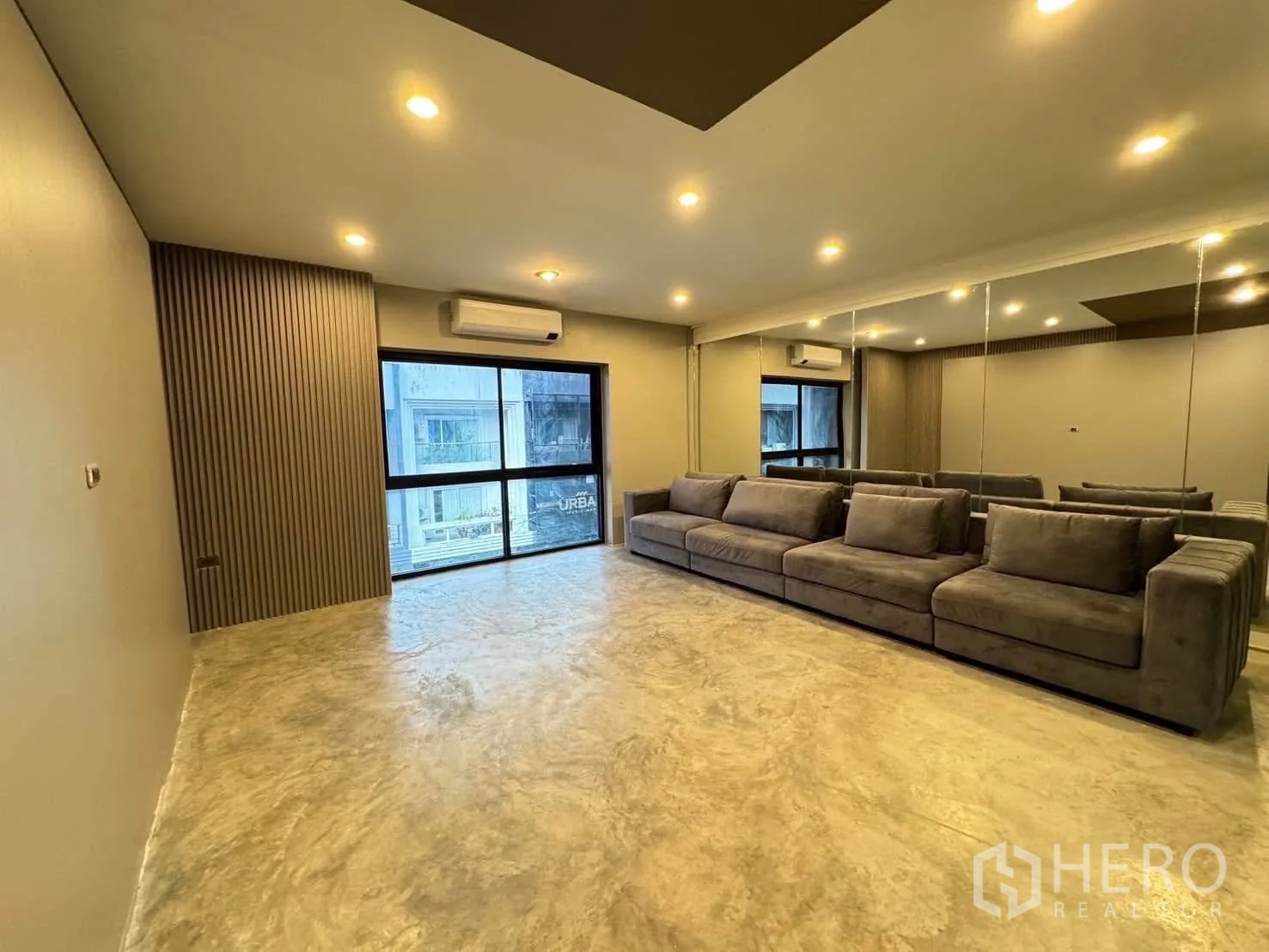 家庭办公室 for rent in Watthana, Bangkok - 休闲区配长灰色沙发、镜面墙、嵌灯与大窗户。