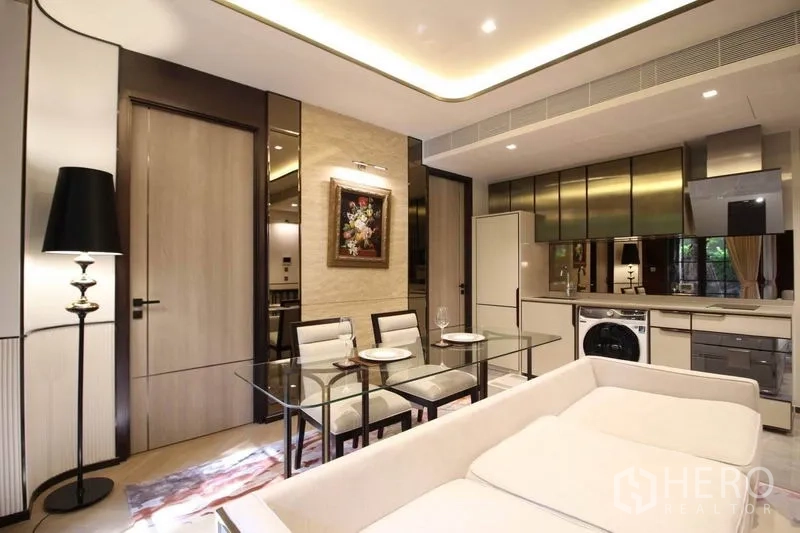 Condominium for rent in Watthana, Bangkok - Contemporary open living space with sofa, tall floor lamp and ceiling cove lights beside the kitchen.