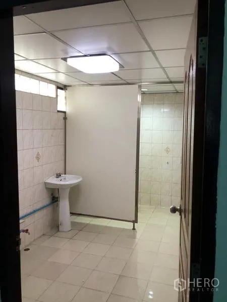 Warehouse for rent in Sai Noi, Nonthaburi - Clean tiled restroom with sink, partition and ceiling light.