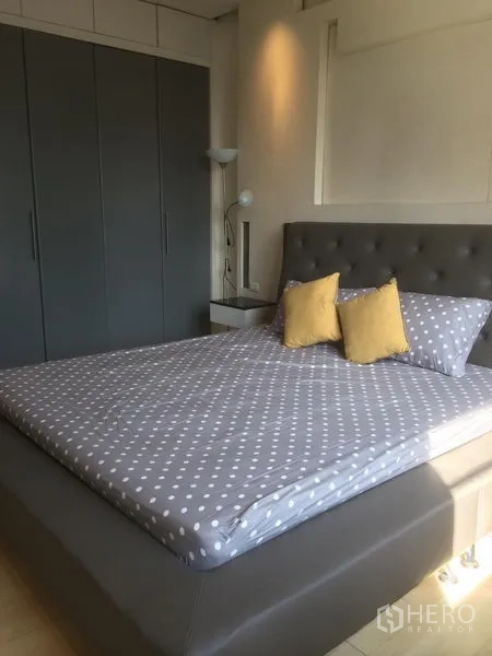 公寓 出租在Khlong Toei, Bangkok - 主卧配软包床头、波点床品与整面灰色衣柜，采光良好。