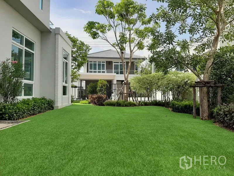 Detached House for rent in Samut Prakan - Spacious private garden with lush green lawn and trees facing the house.