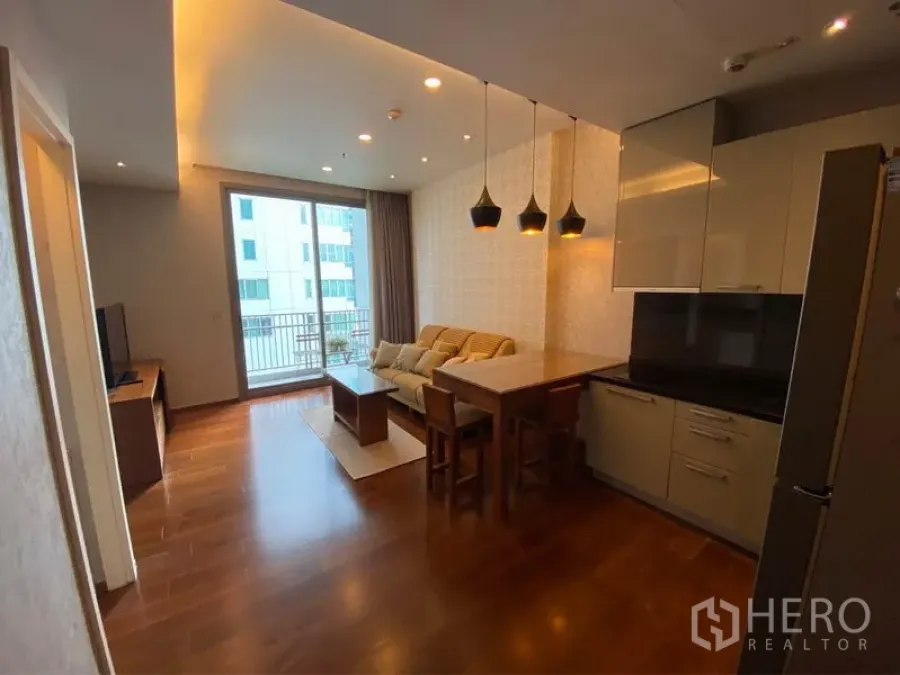 公寓 出租或出售在Watthana, Bangkok - 通罗公寓的开放式客厅，木地板、现代厨房、吊灯与通向阳台的落地门。