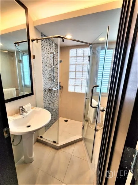 公寓 出租在Bang Rak, Bangkok - 明亮第二卧室，特大床、橙色抱枕、电视柜、衣柜、大窗与木地板。