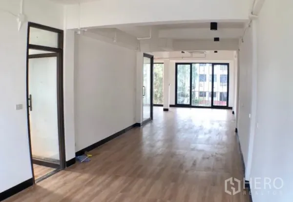 办公空间 出租在Ratchathewi, Bangkok - 修长的开放式办公区，木地板、白色天花，滑动玻璃隔断连接会议室。