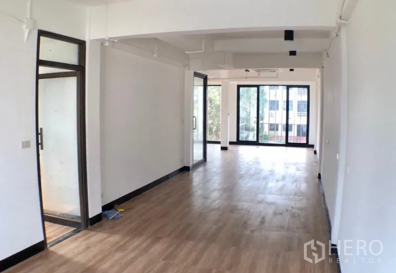 办公空间 出租在Ratchathewi, Bangkok - 修长的开放式办公区，木地板、白色天花，滑动玻璃隔断连接会议室。