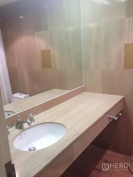 Condominium for rent in Pathum Wan, Bangkok - Modern bathroom with wide vanity, under-mount sink and large wall mirror.