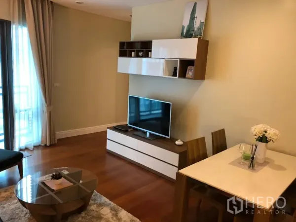 公寓 出租或出售在Khlong Toei, Bangkok - 客厅内的电视柜与壁柜，旁边是双人餐桌与木地板。