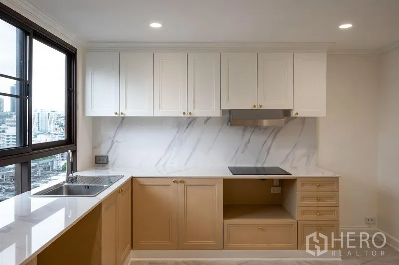 Condominium for sale in Watthana, Bangkok - Kitchen close-up showing white countertops, shaker cabinets and a city outlook.