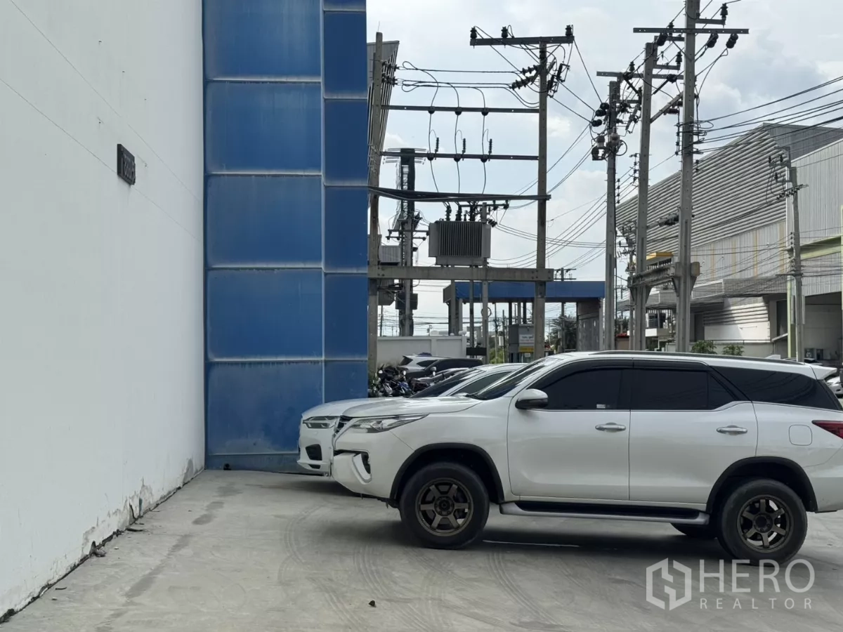 工厂 出租或出售在Bang Phli, Samut Prakan - 入口停车区，车辆与电力设施可见。