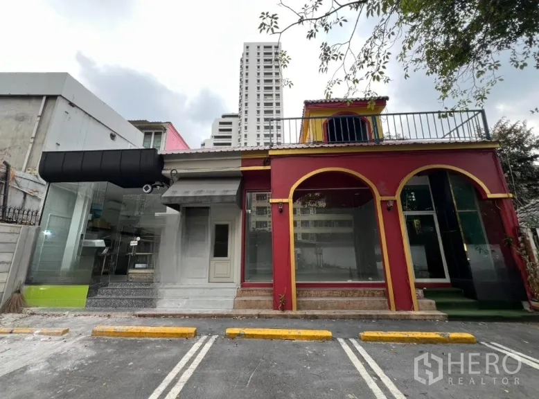 零售空间 for rent in Watthana, Bangkok - 临街零售铺面，红色拱形外立面，落地玻璃与门前划线停车位。