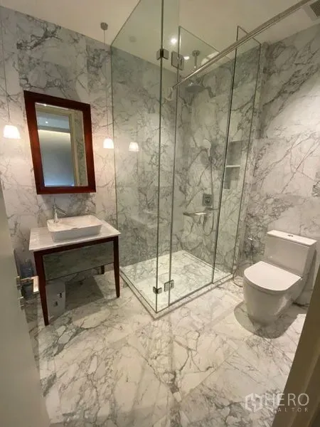 คอนโด ให้เช่าหรือขายในWatthana, Bangkok - ห้องน้ำหินอ่อน พร้อมฝักบัวกระจก อ่างล้างหน้า และโถสุขภัณฑ์ ใต้โคมไฟแขวน