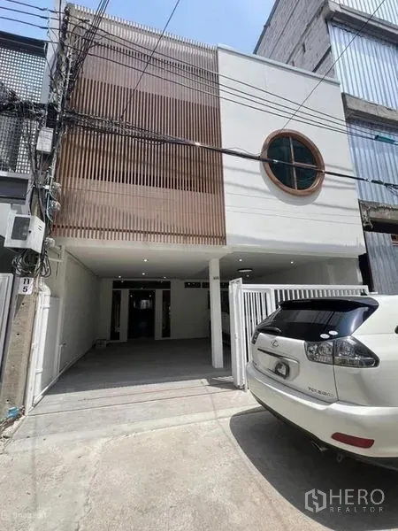 Townhouse for rent in Khlong Toei, Bangkok - Modern two-storey townhouse facade with carport, wood slat feature and round window in Ekkamai.