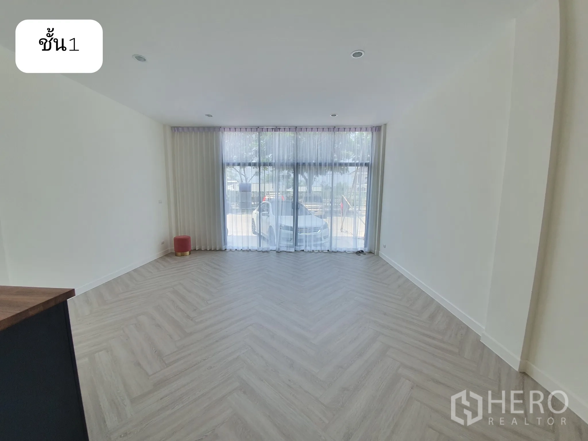 Home Office for rent or sale in Prawet, Bangkok - Front room with full-height windows, sheer curtains and herringbone flooring on the ground floor.