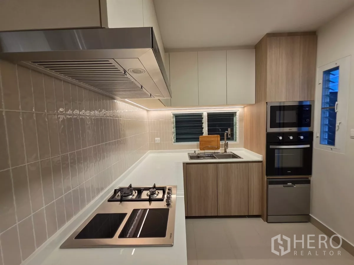 Detached House for rent in Bang Phli, Samut Prakan - U-shaped kitchen with gas hob, sink, oven, microwave and wood cabinetry.