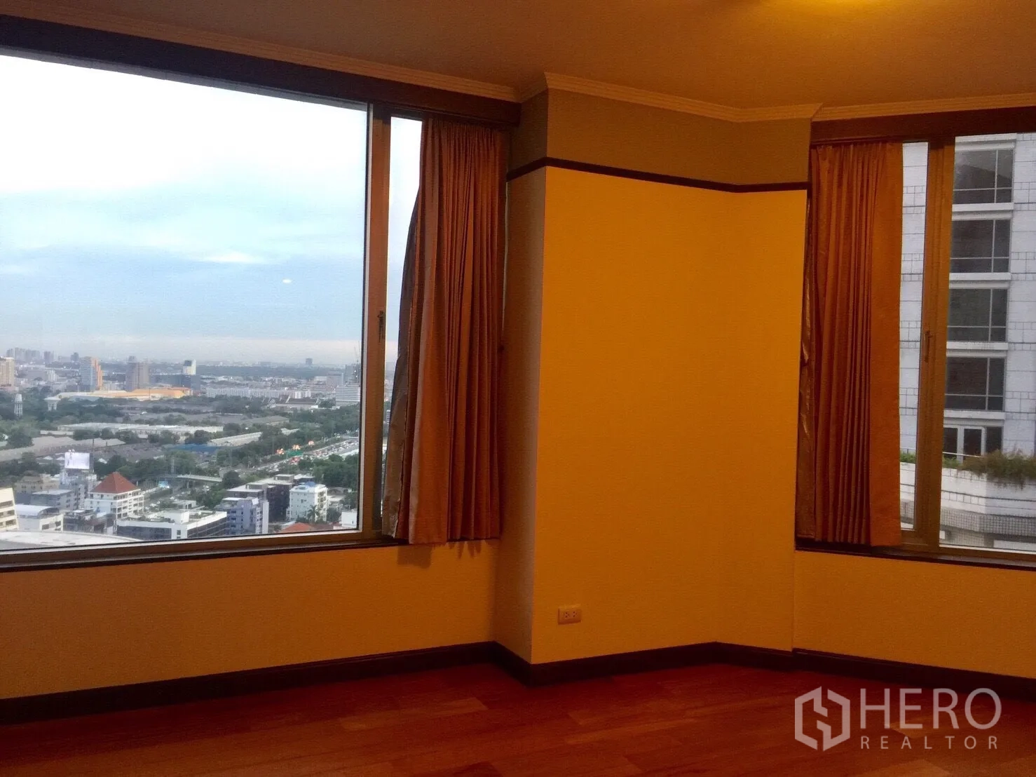 Condominium for rent in Pathum Wan, Bangkok - Corner room with expansive windows framing the Bangkok skyline and nearby towers.