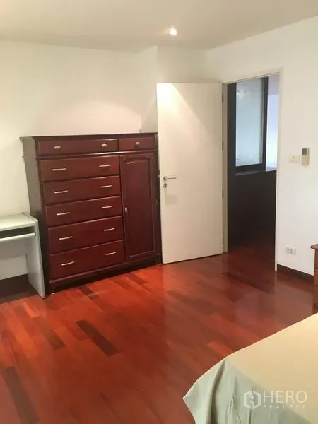 Condominium for rent or sale in Watthana, Bangkok - Bedroom with hardwood floors, tall wooden dresser and recessed lighting.