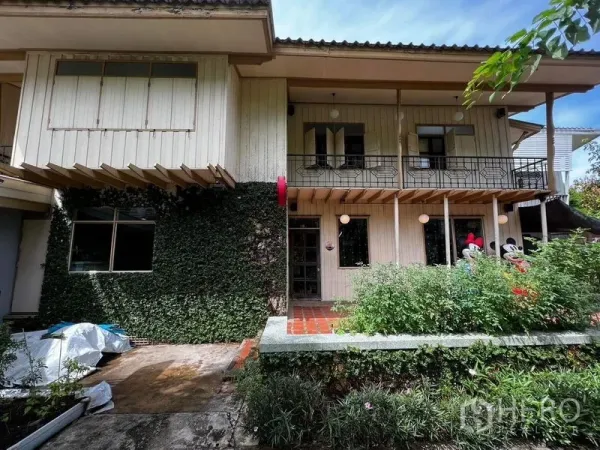 ทาวน์เฮาส์ ให้เช่า - ด้านหน้าทาวน์เฮ้าส์สองชั้น ผนังไม้ปกคลุมด้วยไม้เลื้อย มีระเบียงและสวนหน้าบ้าน