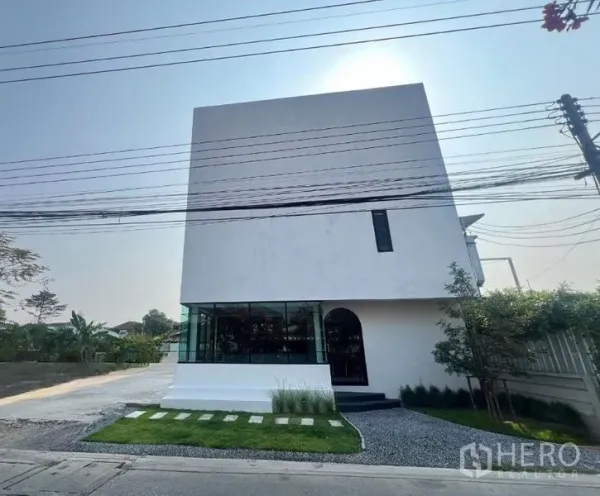 สำนักงานที่บ้าน ขายในThanyaburi, Pathum Thani - อาคารโฮมออฟฟิศสีขาวทรงโมเดิร์น หน้ากระจกมุม โถงทางเข้า สนามหญ้าเล็กและทางรถกว้างในธัญบุรี