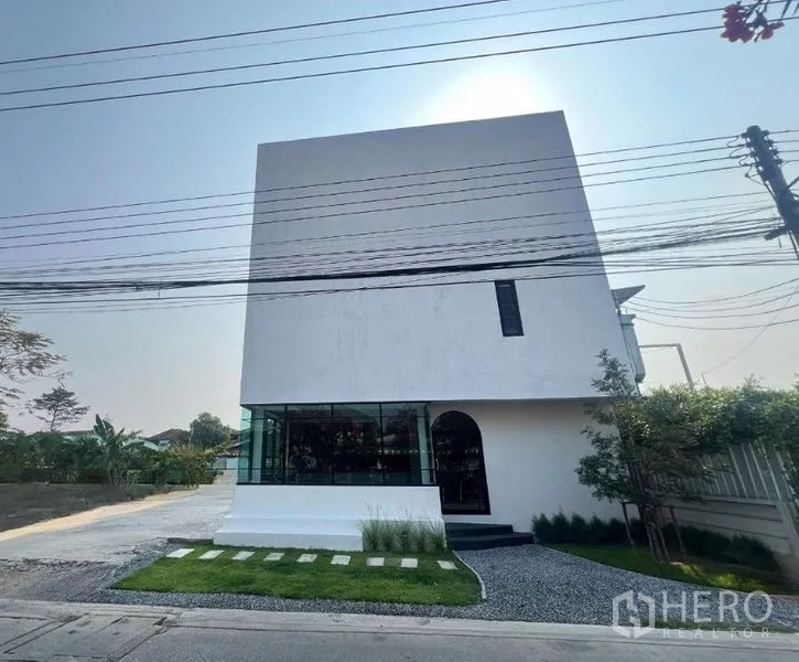 สำนักงานที่บ้าน ขายในThanyaburi, Pathum Thani - อาคารโฮมออฟฟิศสีขาวทรงโมเดิร์น หน้ากระจกมุม โถงทางเข้า สนามหญ้าเล็กและทางรถกว้างในธัญบุรี