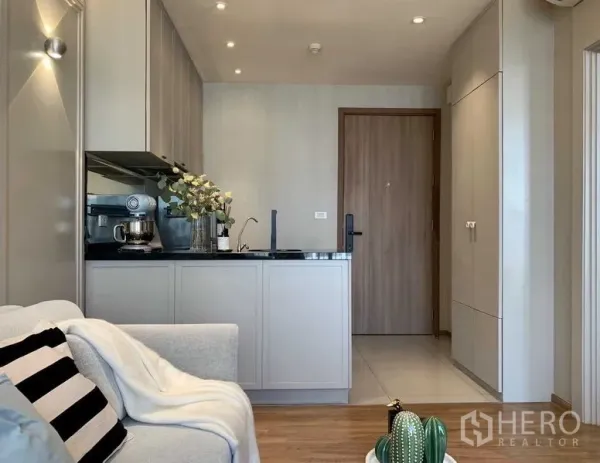 Condominium for rent or sale in Watthana, Bangkok - Compact open kitchen with black countertop and built-in cabinets beside entry.