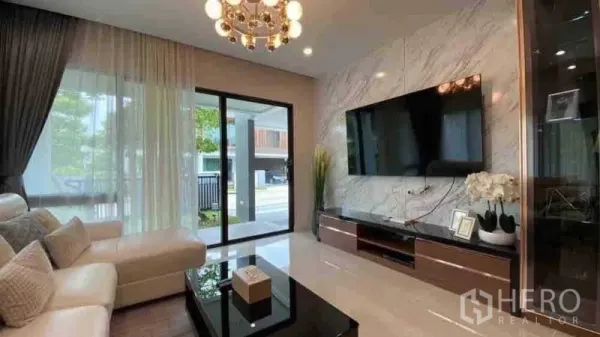 Detached House for rent or sale in Prawet, Bangkok - Bright lounge with sliding glass doors to the patio and a large TV.