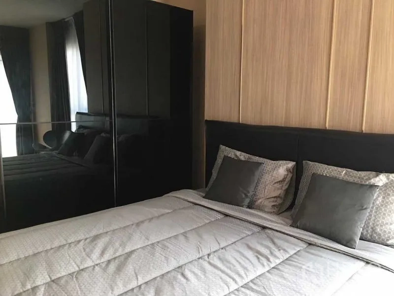 Condominium for sale in Khlong San, Bangkok - Master bedroom with padded headboard, grey bedding and glossy black wardrobe.