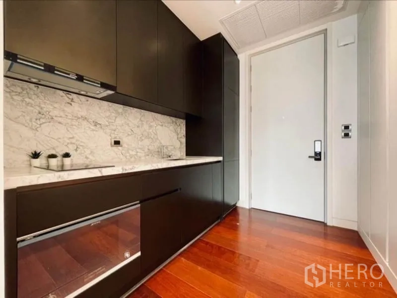 公寓 出租在Watthana, Bangkok - 走廊式厨房，深色柜体与大理石防溅板
