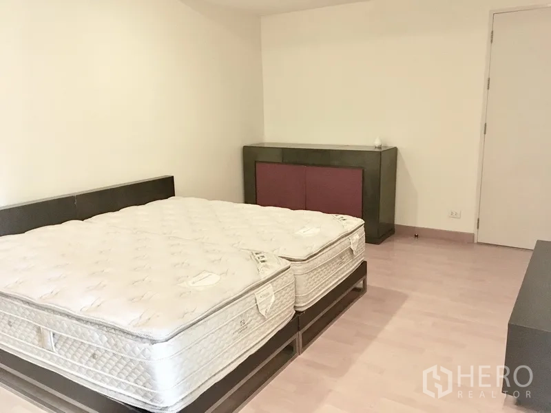 Condominium for rent in Khlong Toei, Bangkok - Large second bedroom with twin mattresses on platform bed and minimalist cabinetry.