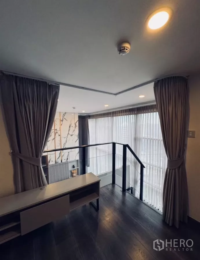 Condominium for rent in Chatuchak, Bangkok - Open mezzanine space with railing and curtains overlooking the living room.