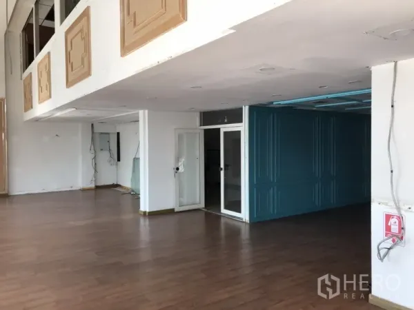 零售空间 出租在Watthana, Bangkok - 展厅区域，带玻璃门、白色墙面和蓝绿色隔断。