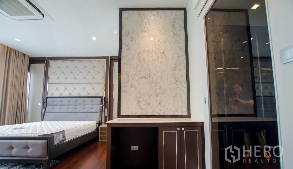 Detached House for rent in Bang Bon, Bangkok - Bedroom angle showing marble accent panel and doorway to a walk-in closet.