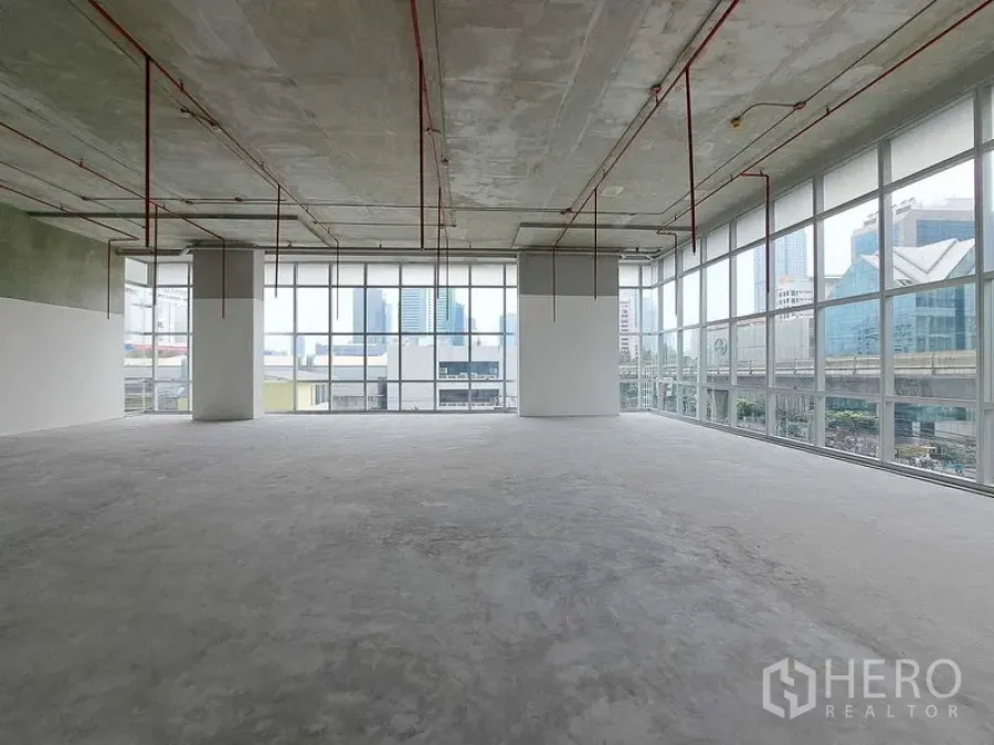 พื้นที่ขายปลีก ให้เช่าในSathon, Bangkok - พื้นที่ค้าปลีกแบบโถงโล่ง กระจกบานสูงรอบด้าน เพดานโชว์งานระบบ พื้นคอนกรีต มองเห็นวิวเมืองและแนวรถไฟฟ้า BTS ในย่านสาทร กรุงเทพฯ