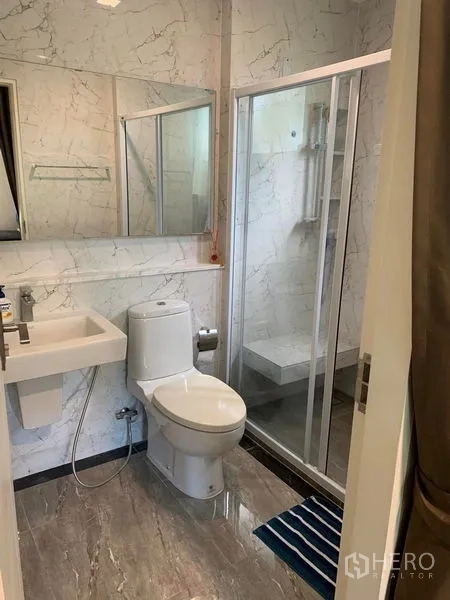 Detached House for rent or sale in Bang Phli, Samut Prakan - Bathroom with marble-effect walls, glass shower, white sanitary ware and mirror.